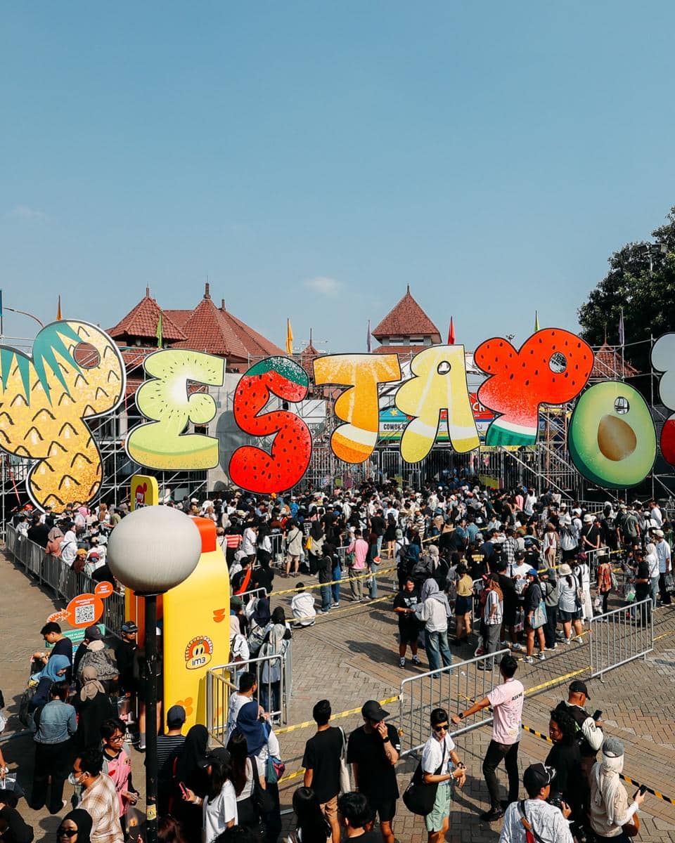 Kerumunan pengunjung antre di pintu masuk festival musik Pestapora dengan dekorasi huruf warna-warni besar di area luar ruangan.