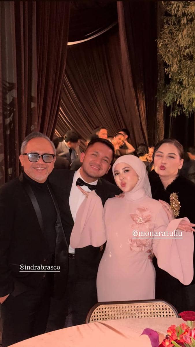 Empat orang berpose bersama mengenakan busana formal di sebuah acara malam dengan latar tirai cokelat dan pencahayaan hangat.