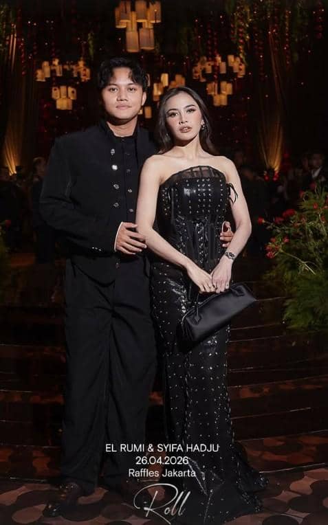 Sepasang tamu berpakaian formal berpose di resepsi pernikahan El Rumi dan Syifa Hadju di Raffles Jakarta dengan latar dekorasi elegan.