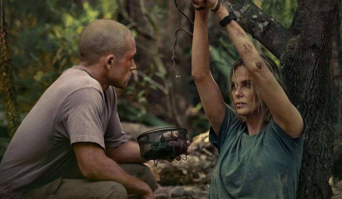 Seorang pria berbicara dengan seorang wanita yang terikat di pohon di tengah hutan, keduanya tampak lelah dan terluka.