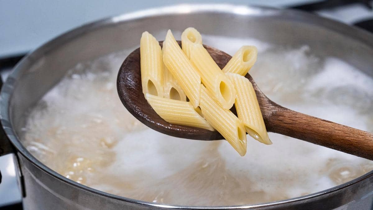 Ilustrasi panci berisi macaroni yang direbus dalam air mendidih untuk menyiapkan hidangan pasta di dapur.