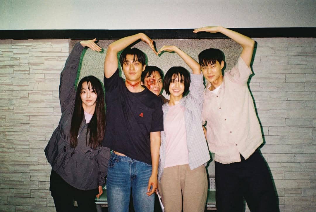 Para pemeran drama Korea If Wishes Could Kill berpose ceria di belakang layar sambil membentuk simbol hati dengan tangan mereka.