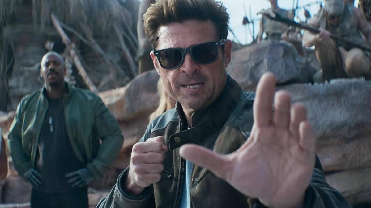 Seorang pria mengenakan jaket kulit dan kacamata hitam bersiap bertarung di lokasi berbatu dalam adegan film Mortal Kombat 2.