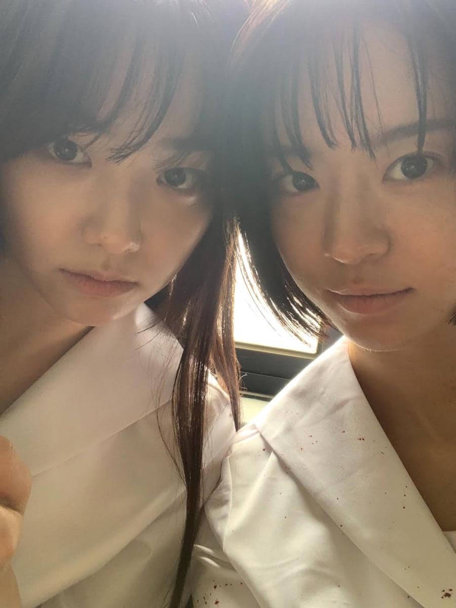 Dua pemeran drama Korea If Wishes Could Kill berpose bersama di belakang layar dengan mengenakan seragam putih.