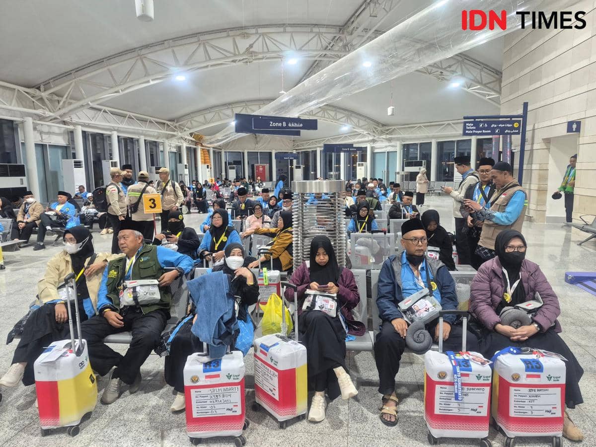 Rombongan jemaah haji asal Cimahi duduk di area kedatangan Bandara Prince Mohammed bin Abdul Aziz, Madinah, dengan koper dan perlengkapan haji.