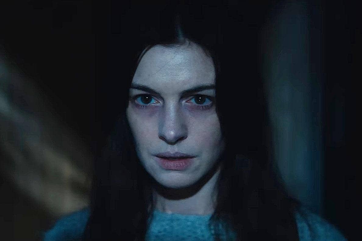 Seorang perempuan berwajah pucat dengan ekspresi tegang berdiri di ruangan gelap dalam cuplikan trailer film Verity.