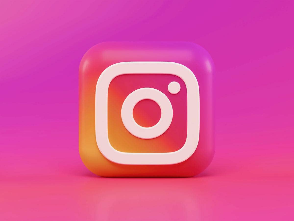 Ilustrasi logo Instagram berwarna putih di atas latar gradasi oranye, merah muda, dan ungu dengan desain tiga dimensi.
