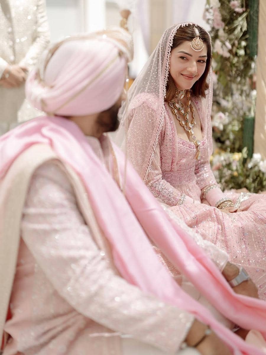 Pasangan pengantin mengenakan busana tradisional India berwarna merah muda lembut saat upacara pernikahan dengan nuansa elegan.