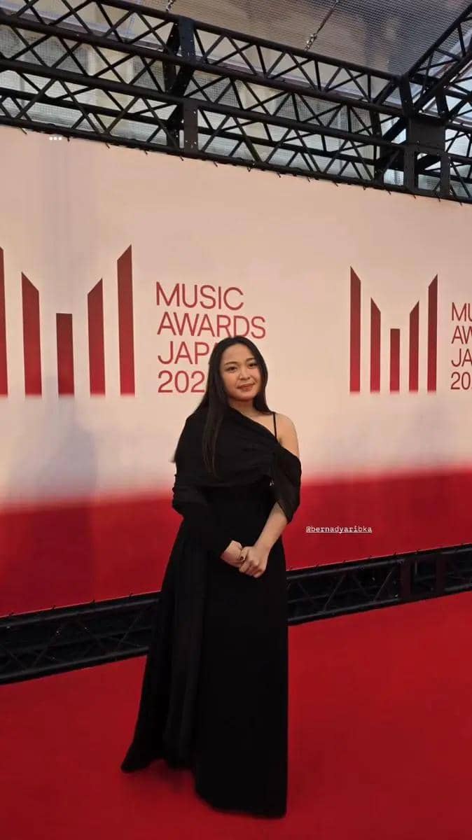 Bernadya mengenakan gaun hitam elegan berpose di karpet merah acara Music Awards Japan 2025 dengan latar logo acara.