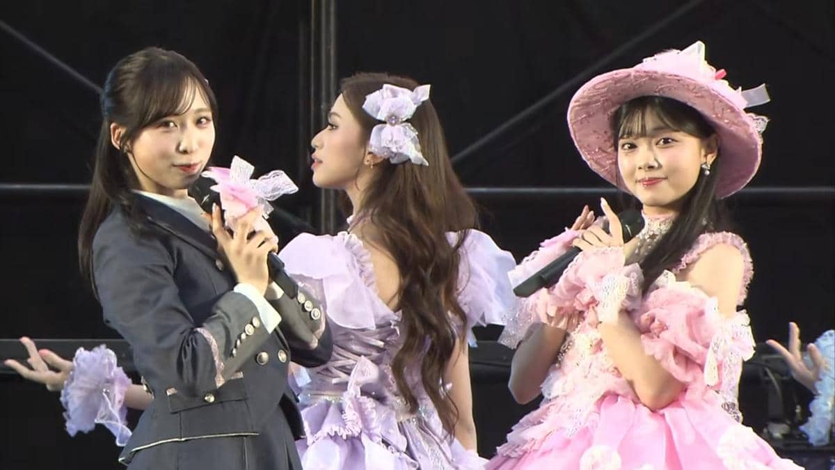 Anggota JKT48 tampil di panggung acara handshake AKB48 2026 mengenakan kostum berwarna pastel sambil memegang mikrofon.