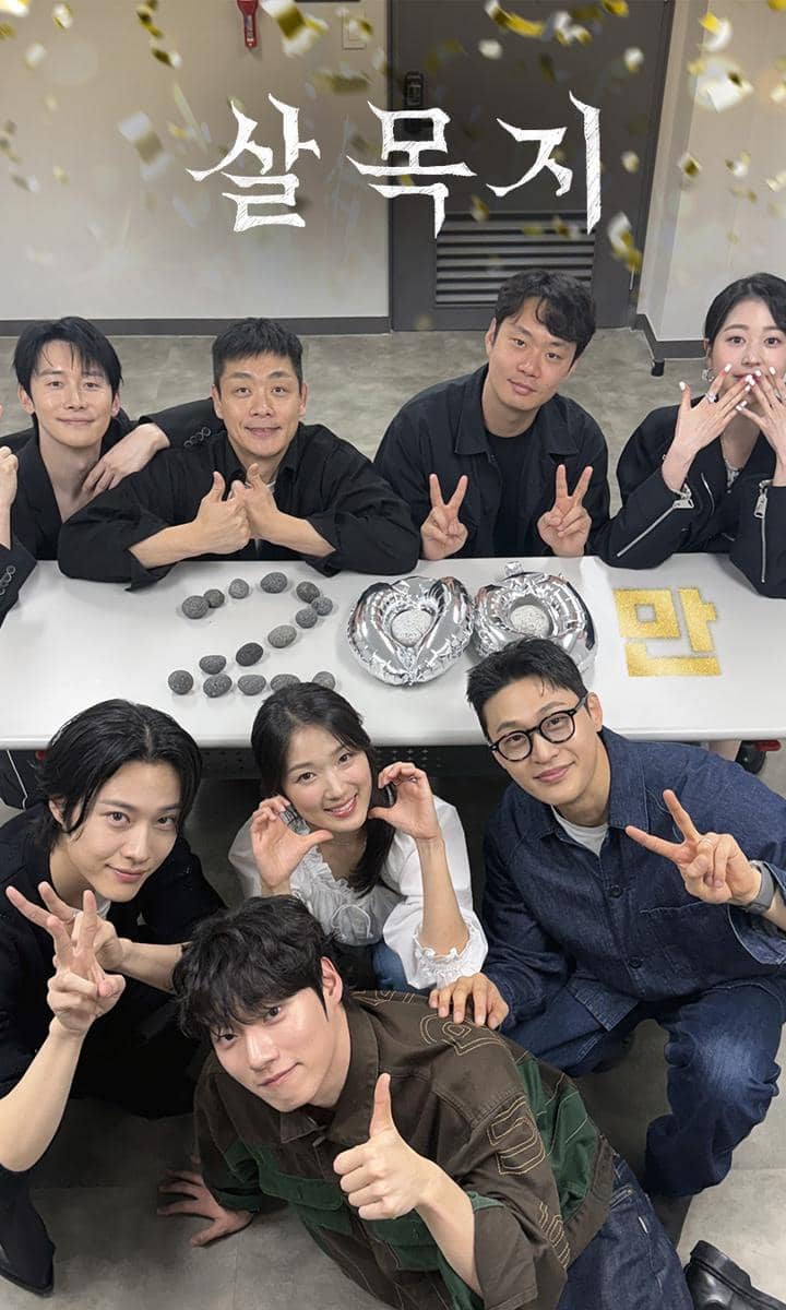 Para pemain dan kru Salmokji: Whispering Water berpose bersama di depan meja dengan dekorasi perayaan di atasnya.