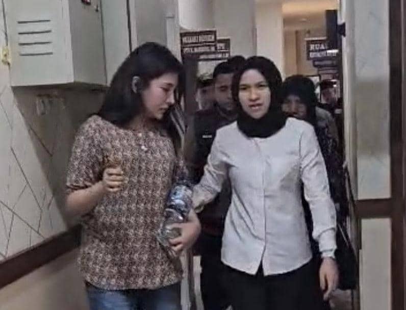 Petugas kepolisian mengawal seorang perempuan yang diduga finalis Putri Indonesia Riau di dalam gedung kepolisian Polda Riau.