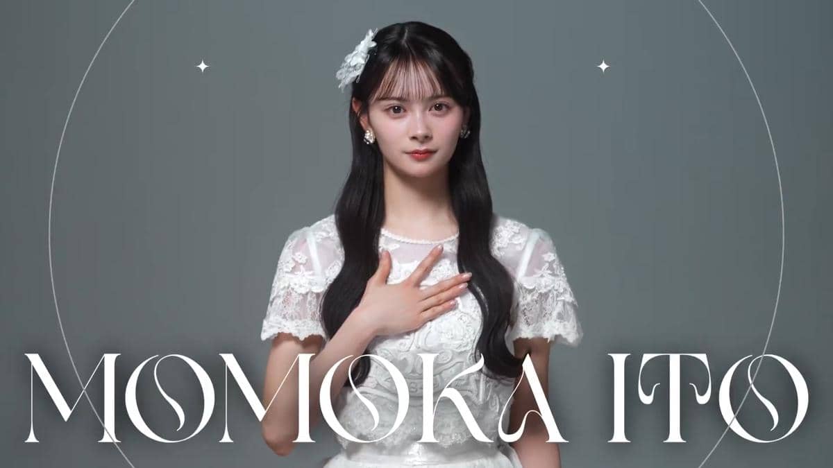 Ito Momoka berambut panjang mengenakan gaun renda putih dengan hiasan bunga di rambut, berdiri dengan tangan di dada di latar abu-abu.