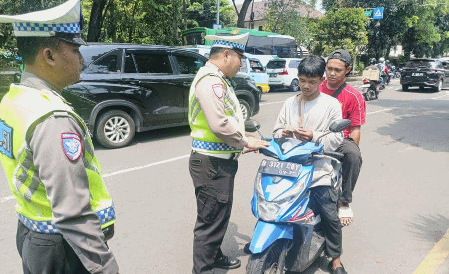 Polisi lalu lintas di Tangerang memeriksa pengendara motor dengan ETLE genggam di jalan raya yang ramai kendaraan.