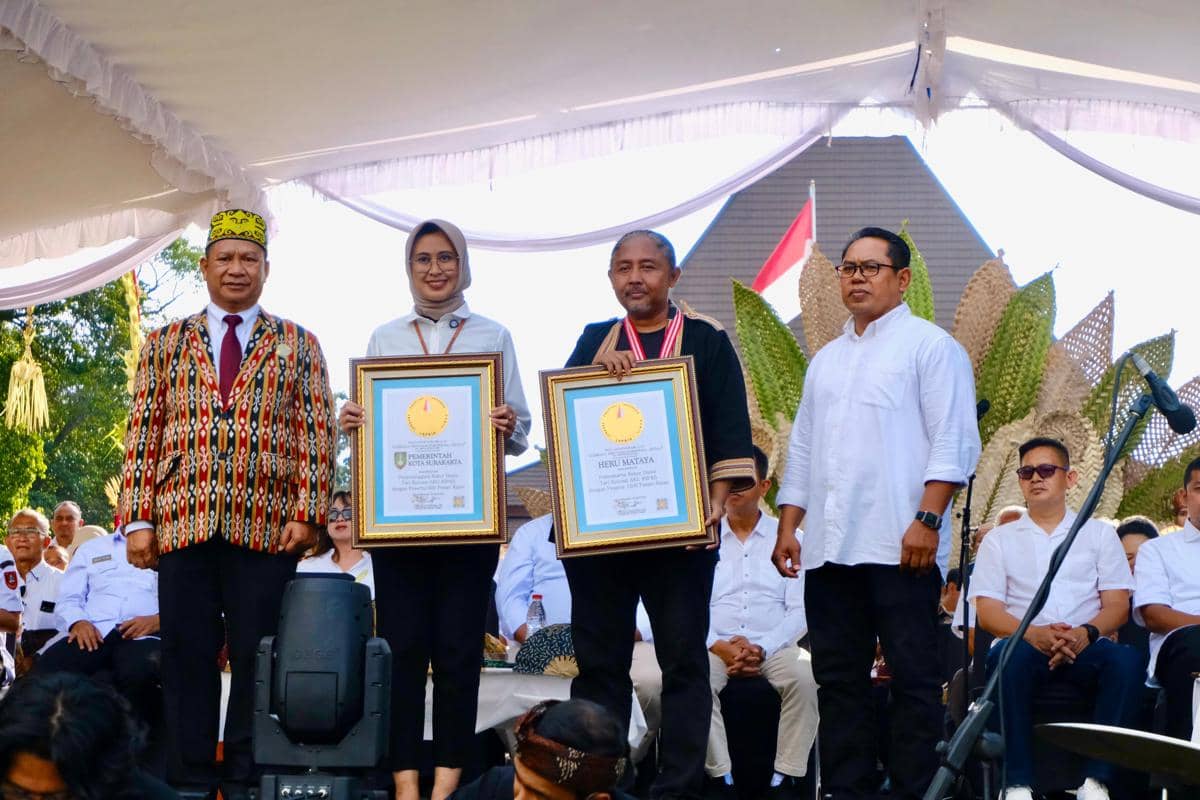 Beberapa orang berdiri di atas panggung saat penyerahan piagam rekor MURI kepada perwakilan Pemerintah Kota Surakarta dalam sebuah acara resmi.