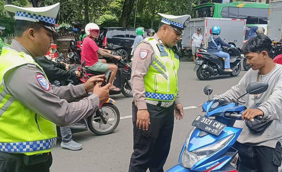 Dua polisi lalu lintas di Tangerang memeriksa pengendara motor menggunakan perangkat ETLE genggam di jalan raya yang ramai.