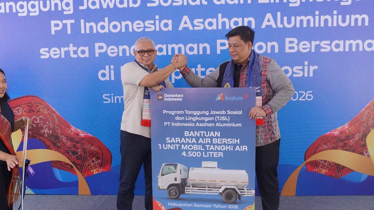 Dua pria berjabat tangan sambil memegang papan simbolis bantuan mobil tangki air 4.500 liter dari PT Inalum dalam program TJSL di Samosir.