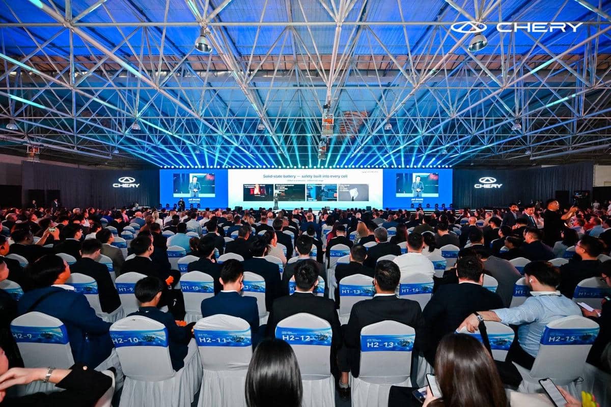 Suasana Chery Brand International Summit 2026 dengan peserta memenuhi ruangan besar dan panggung utama menampilkan presentasi teknologi.