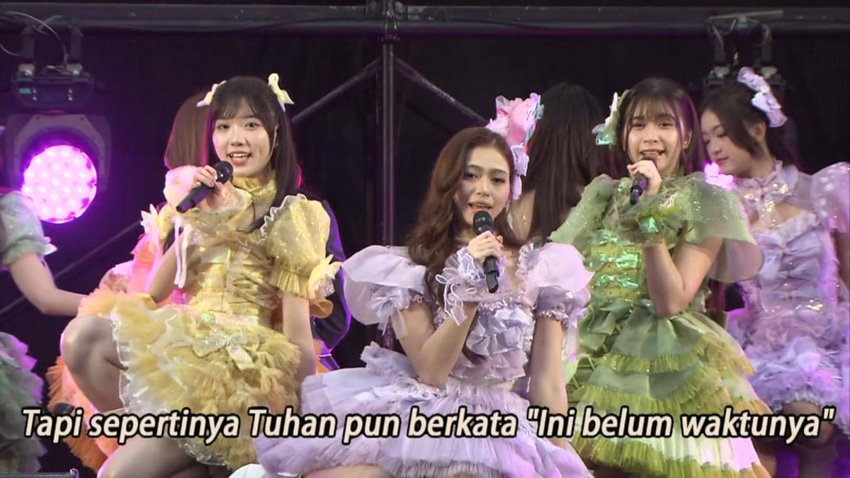 Anggota JKT48 tampil di panggung acara handshake AKB48 2026 mengenakan kostum warna-warni sambil bernyanyi dengan mikrofon.