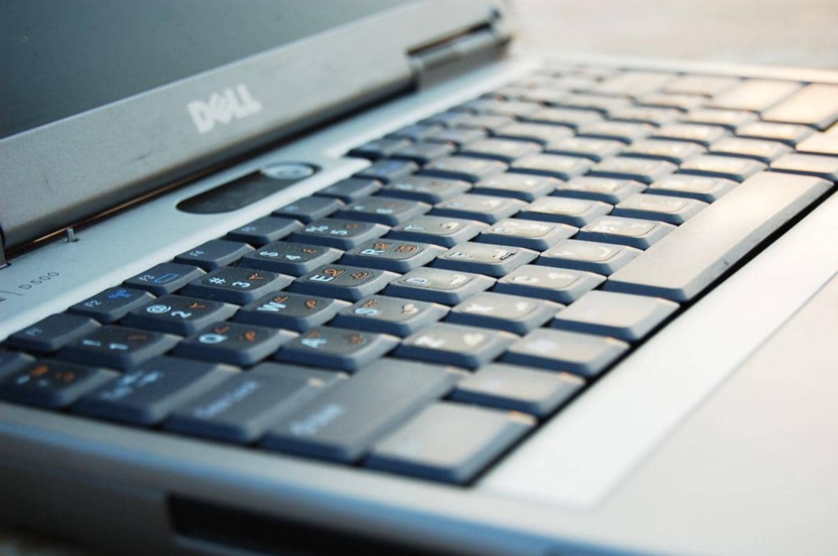 Tampilan dekat keyboard dan bagian layar laptop Dell Latitude berwarna abu-abu dengan pencahayaan alami.