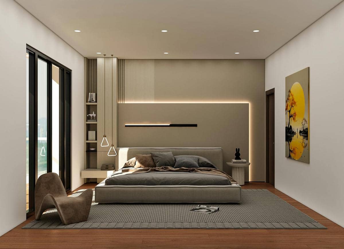 Kamar tidur modern dengan pencahayaan hangat, tempat tidur besar berwarna abu-abu, kursi cokelat, dan lukisan dinding bernuansa kuning.