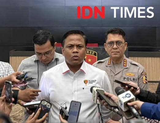 Seorang pejabat kepolisian memberikan keterangan pers di hadapan wartawan dengan beberapa mikrofon dan kamera mengarah kepadanya.