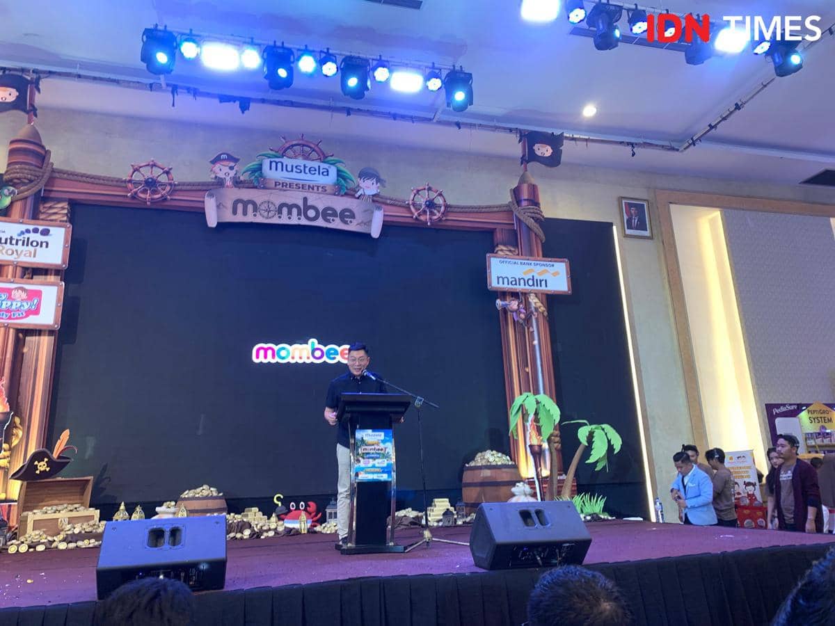 Seorang pembicara berdiri di atas panggung saat pembukaan Mombee Expo 2026 di Medan dengan dekorasi bertema bajak laut dan pencahayaan biru.