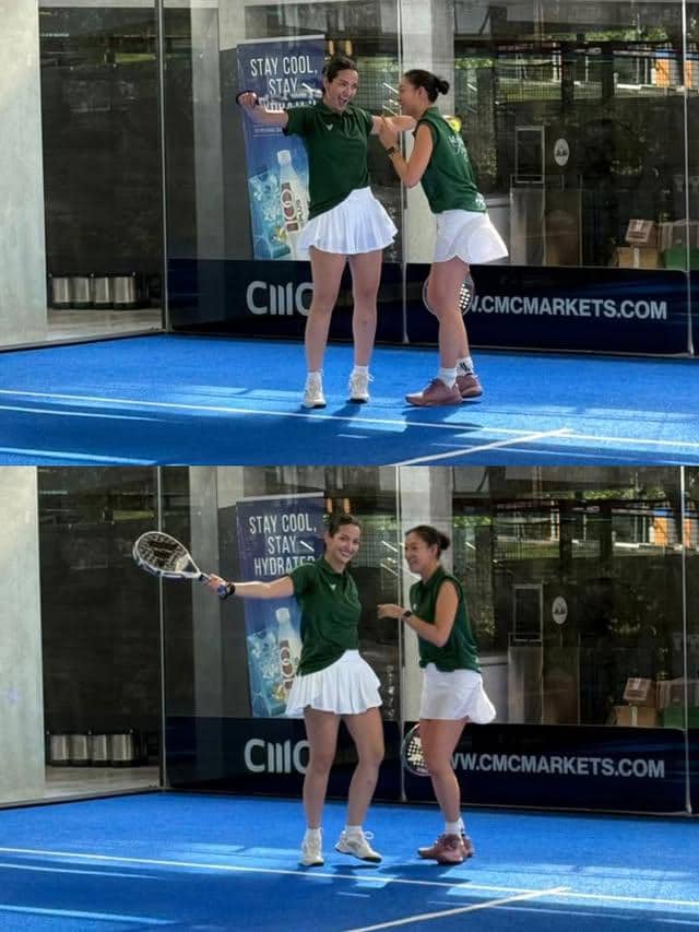 Dua wanita mengenakan seragam hijau dan rok putih bermain padel di lapangan biru dalam turnamen di Singapura, tampak tersenyum bersama.
