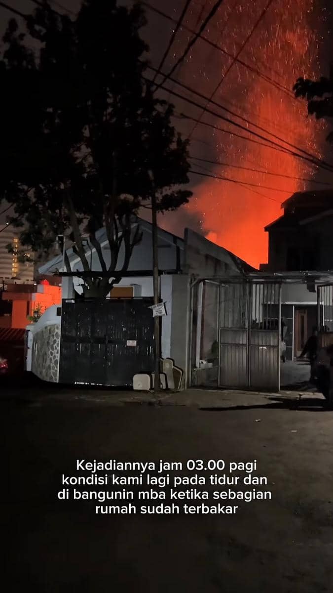 Kobaran api besar terlihat di belakang rumah pada malam hari dengan langit memerah akibat kebakaran yang terjadi dini hari.