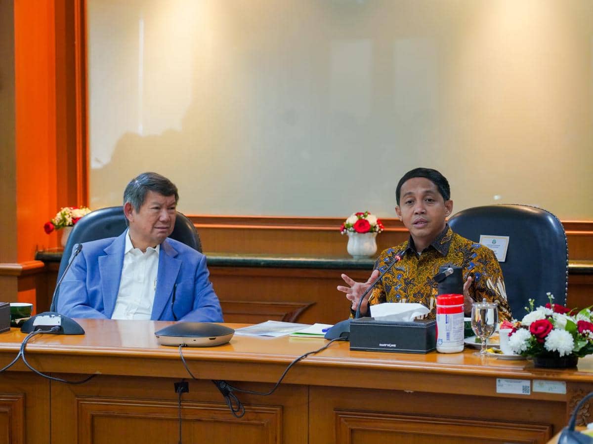 Dua pria duduk di meja rapat Kantor Kemenhut saat pertemuan bersama NGO, dengan mikrofon dan dokumen di depan mereka.