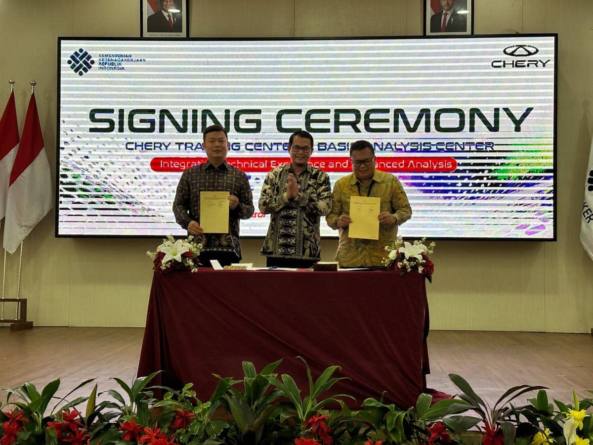Tiga pria berpose sambil memegang dokumen setelah penandatanganan kerja sama antara Chery dan Kementerian Ketenagakerjaan di sebuah aula.