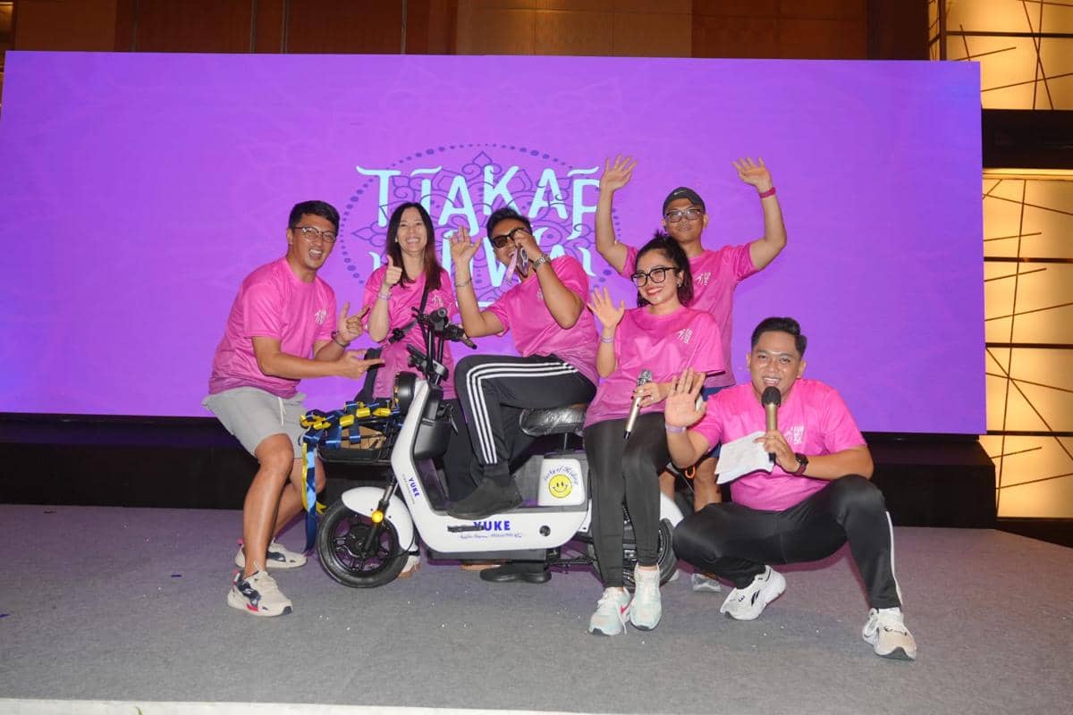 Enam peserta mengenakan kaus pink berpose ceria di atas panggung bersama hadiah sepeda listrik pada acara Fun Walk 5K Aryaduta Medan.