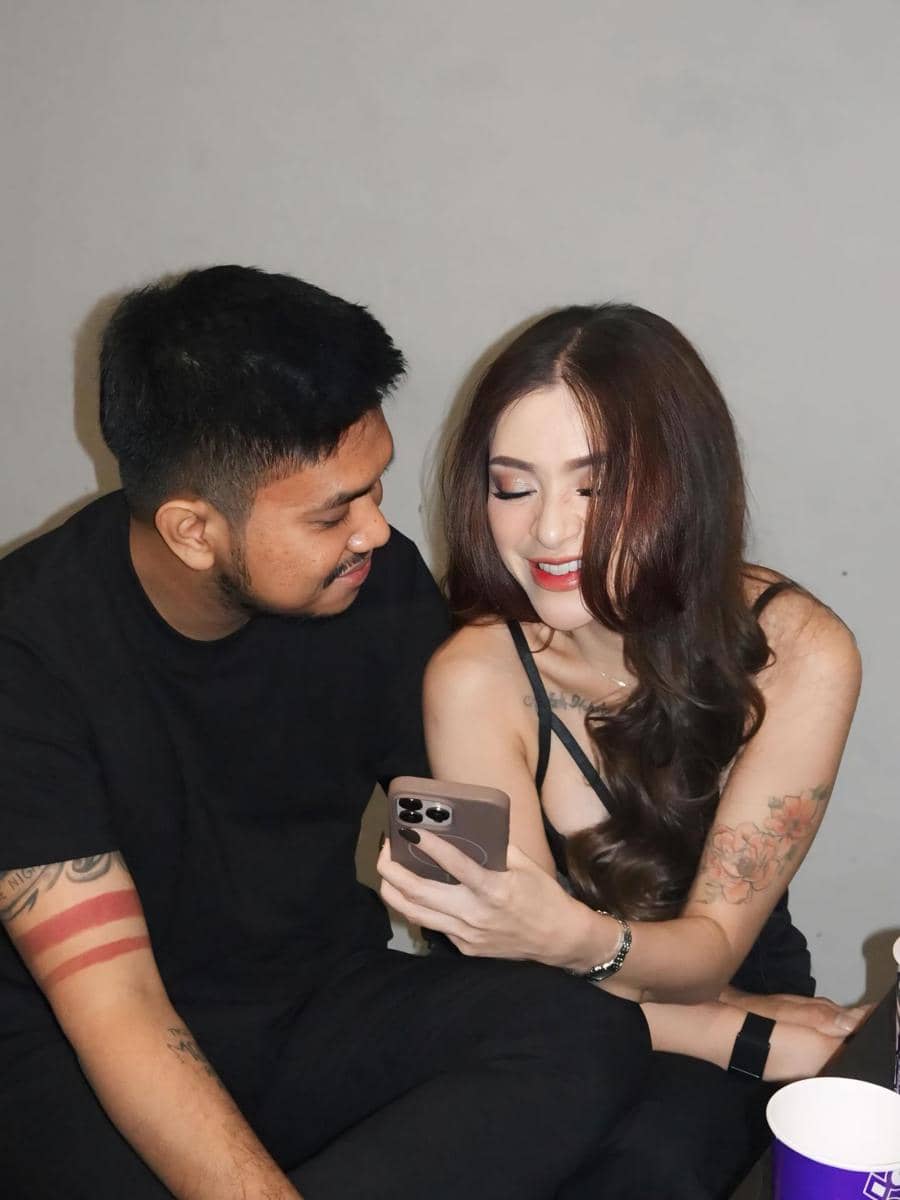 Nathalie Holscher dan Arifat duduk berdampingan sambil tersenyum melihat layar ponsel di tangan wanita dengan latar dinding abu-abu.