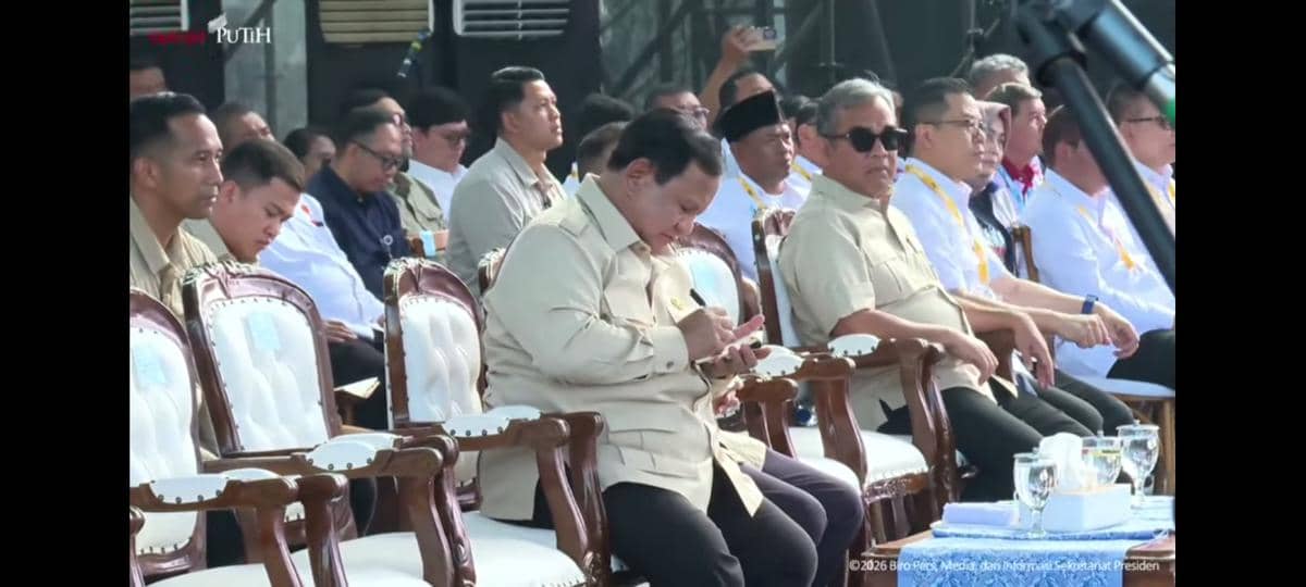 Presiden Prabowo Subianto duduk di kursi acara resmi sambil menulis catatan di kertas saat menghadiri peringatan Hari Buruh (May Day) 2026 di Monas, Jakarta.