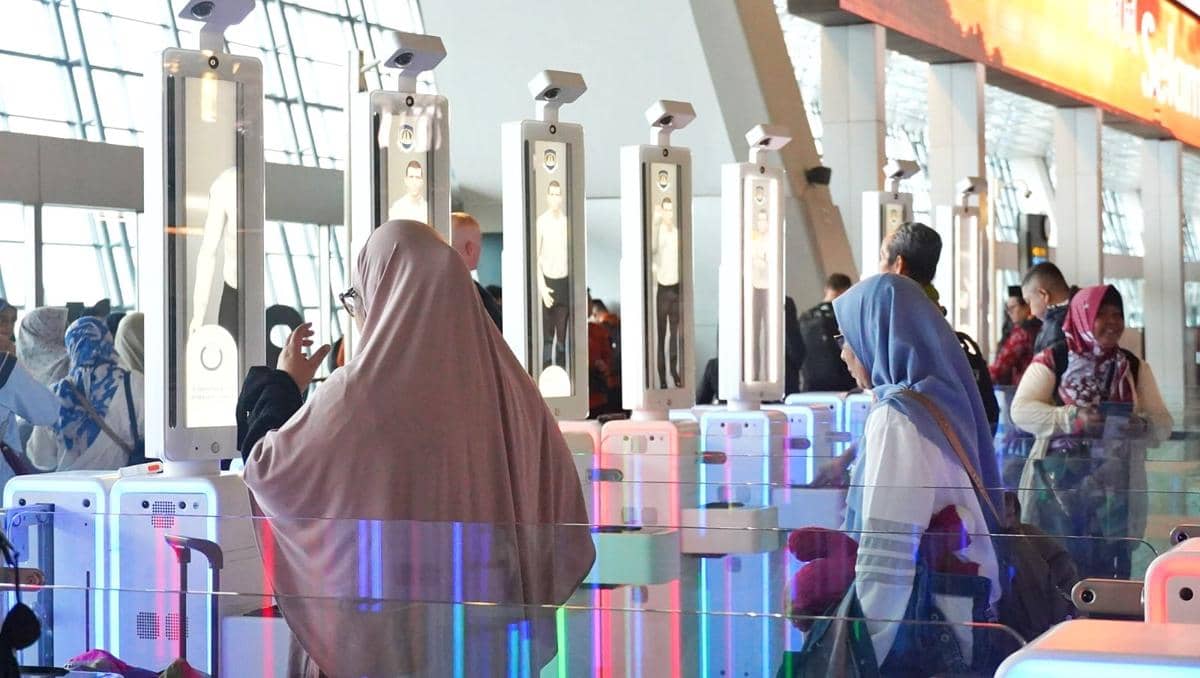 Penumpang melintasi tempat pemeriksaan imigrasi otomatis di Bandara Soekarno-Hatta dengan sistem pemindaian wajah modern.