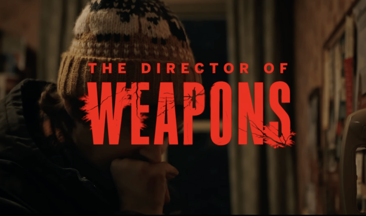 Cuplikan trailer Resident Evil menampilkan seseorang mengenakan topi rajut dengan tulisan besar berwarna merah bertuliskan The Director of Weapons.