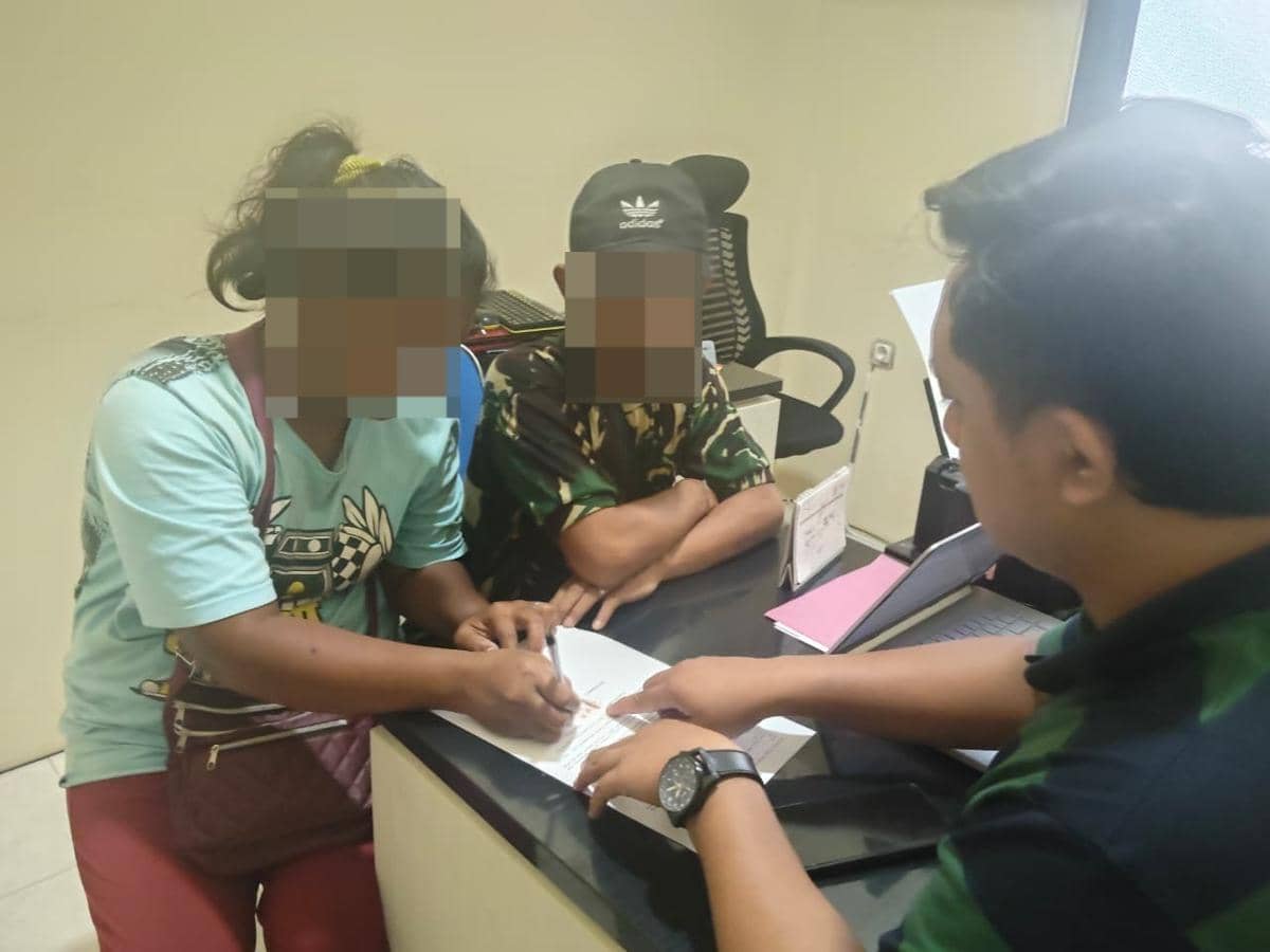 Dua orang dengan wajah diblur sedang duduk di depan petugas kepolisian di meja kantor, menandatangani dokumen resmi.