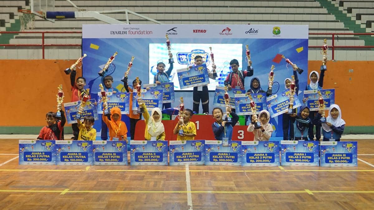 Anak-anak peserta Festival SenengMinton 2026 di Purwokerto berpose di podium sambil memegang piala dan hadiah kemenangan.