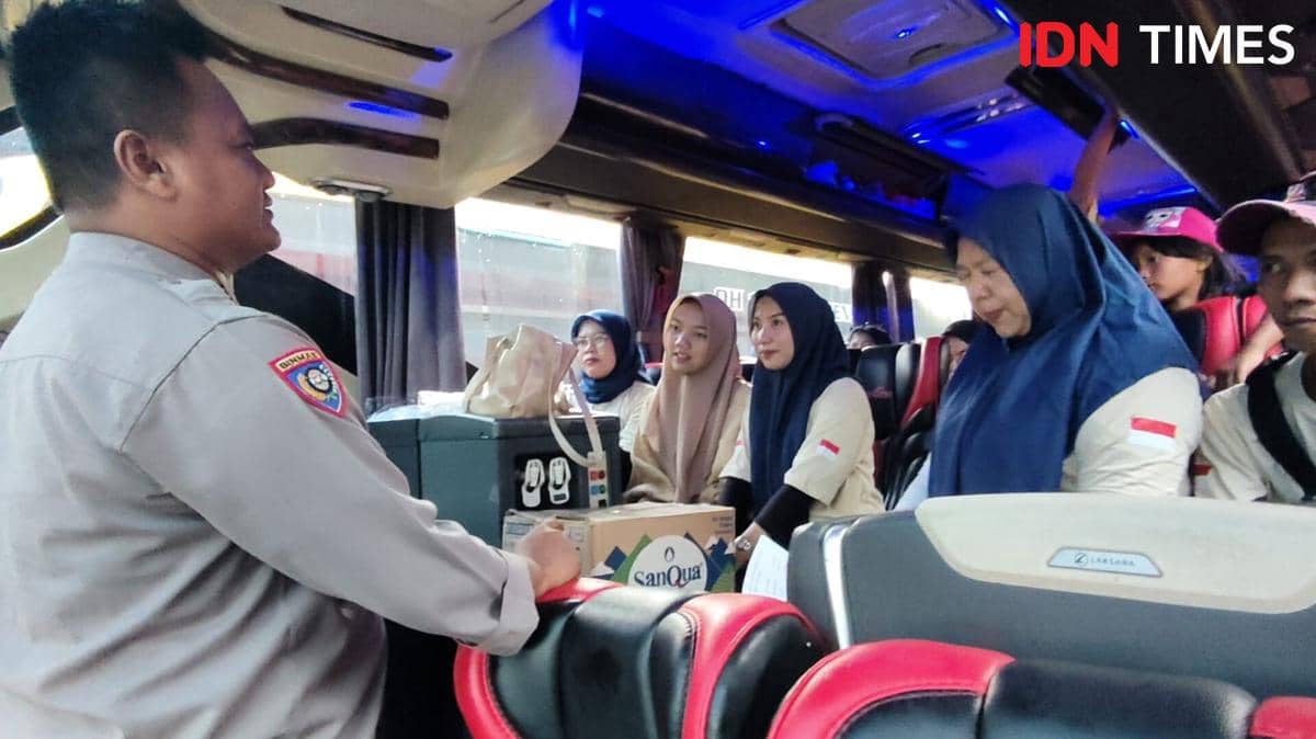 Seorang petugas berbicara dengan sekelompok buruh di dalam bus yang bersiap berangkat dari Tangerang menuju Jakarta untuk peringatan May Day 2026.
