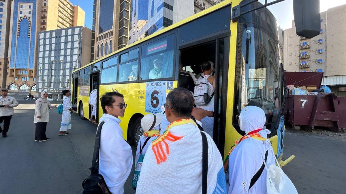Jamaah haji Kloter SOC 1 mengenakan pakaian ihram menaiki bus Shalawat berwarna kuning di area perkotaan menuju Masjidil Haram.