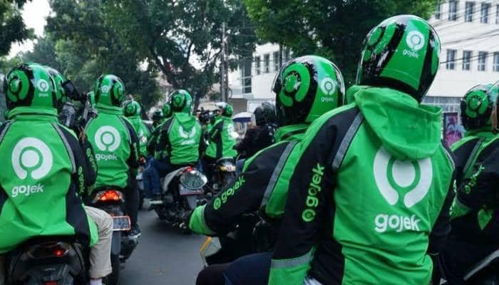 Driver ojek online Gojek memakai jaket hijau dan helm sedang berkumpul di jalan