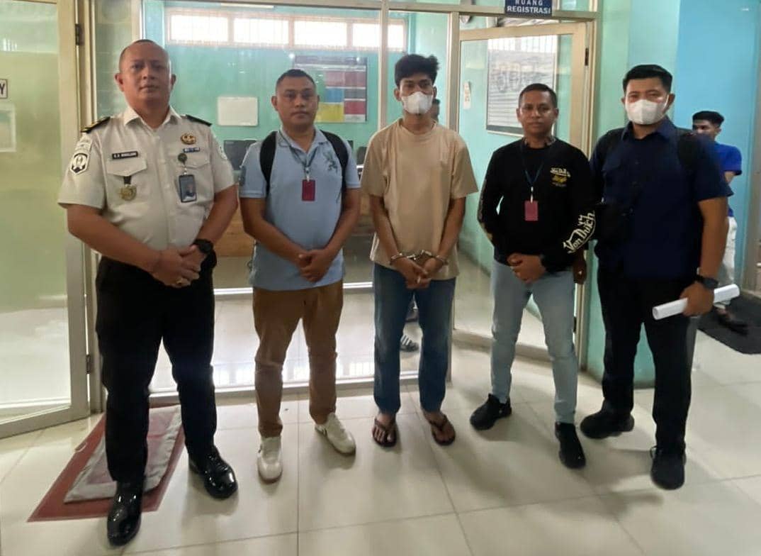 Seorang narapidana di Medan yang diborgol berdiri bersama petugas BNNP NTT di depan ruang registrasi dalam proses pengamanan.