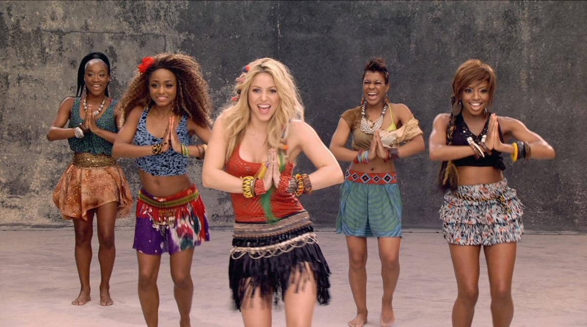 Beberapa penari perempuan menari dengan ekspresi gembira mengenakan busana berwarna cerah dalam cuplikan video musik Waka Waka.