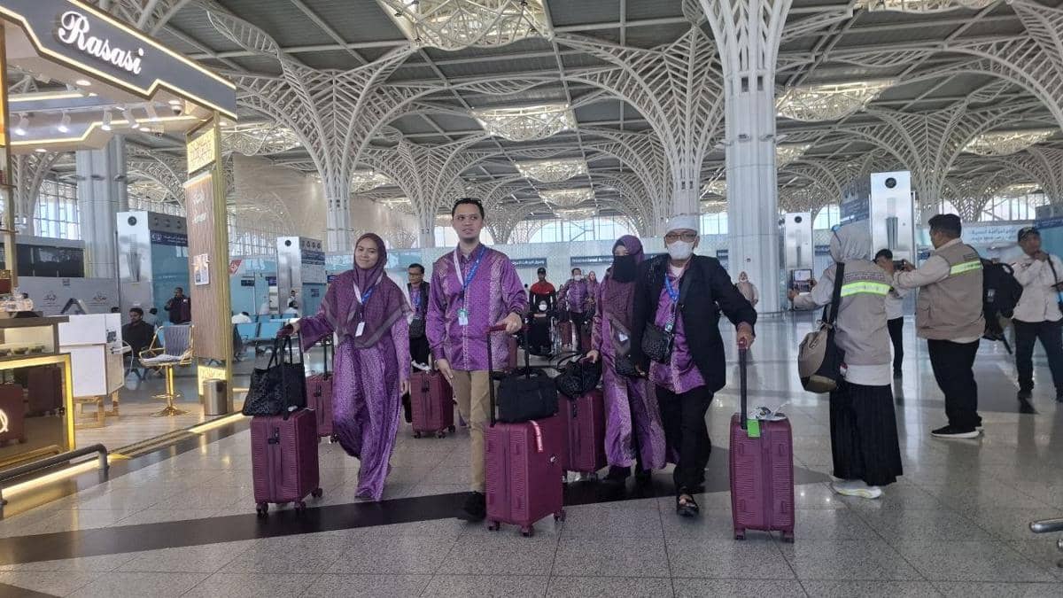 Rombongan jemaah haji khusus mengenakan pakaian ungu tiba di Bandara Internasional Madinah Prince Mohammed bin Abdul Aziz dengan membawa koper.