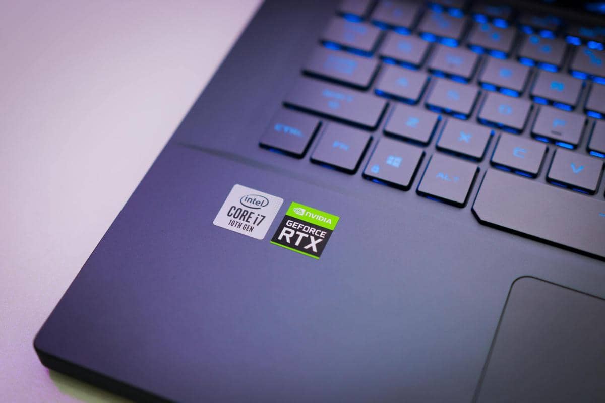 Laptop dengan stiker prosesor Intel Core i7 dan kartu grafis Nvidia GeForce RTX di dekat keyboard berlampu biru.