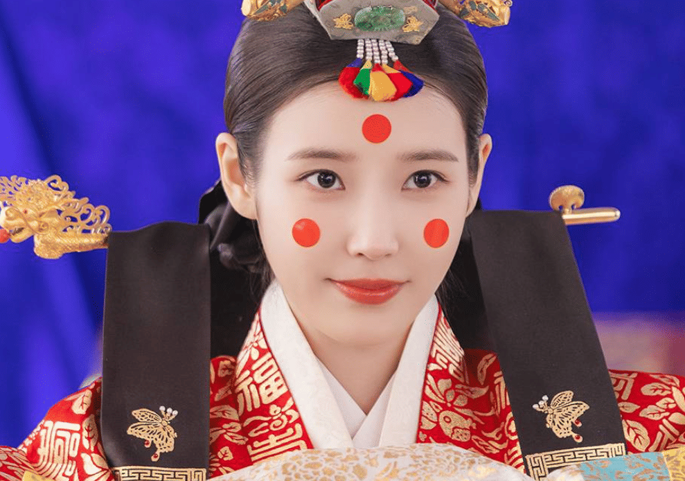 Aktris mengenakan hanbok kerajaan berwarna merah dengan hiasan kepala tradisional dalam cuplikan drama Korea Perfect Crown.