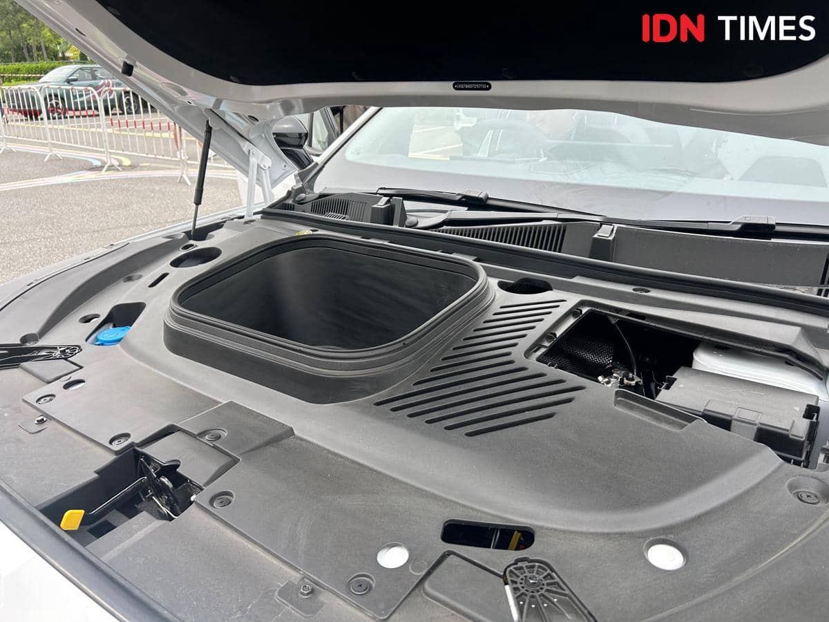 Bagasi depan atau front trunk mobil listrik E5 EV facelift dengan kap mesin terbuka di area parkir luar ruangan.