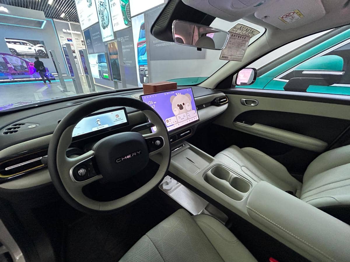 Interior mobil Chery Q dengan desain modern, layar digital besar di dashboard, dan jok kulit berwarna terang yang elegan.