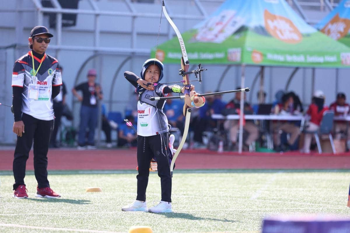 Seorang peserta muda membidik target dengan busur panah dalam ajang MilkLife Archery Challenge Seri 1 2026 di lapangan terbuka.