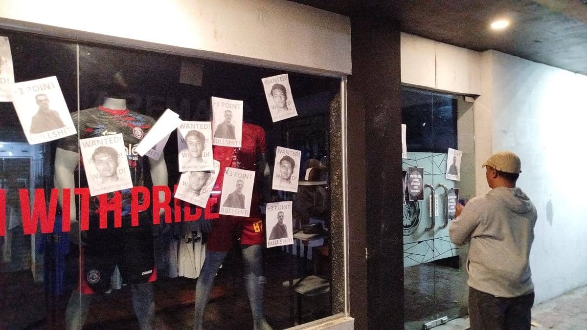 Seorang Aremania menempelkan poster protes di depan kantor Arema FC setelah kekalahan tim dari Persik Kediri.